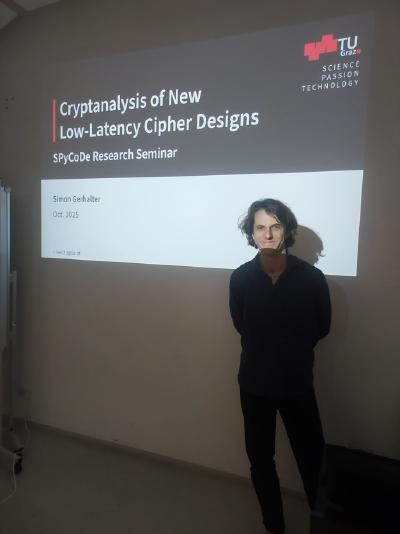Simon Gerhalter stands beside a projected slide titled “Cryptanalysis of New Low-Latency Cipher Designs” with TU Graz logo visible.