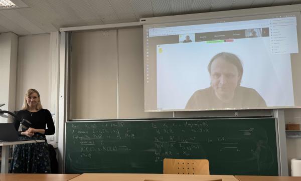 Barbara Gigerl is giving a presentation at the seminar. On the screen, Krzysztof Pietrzak is displayed asking a question
